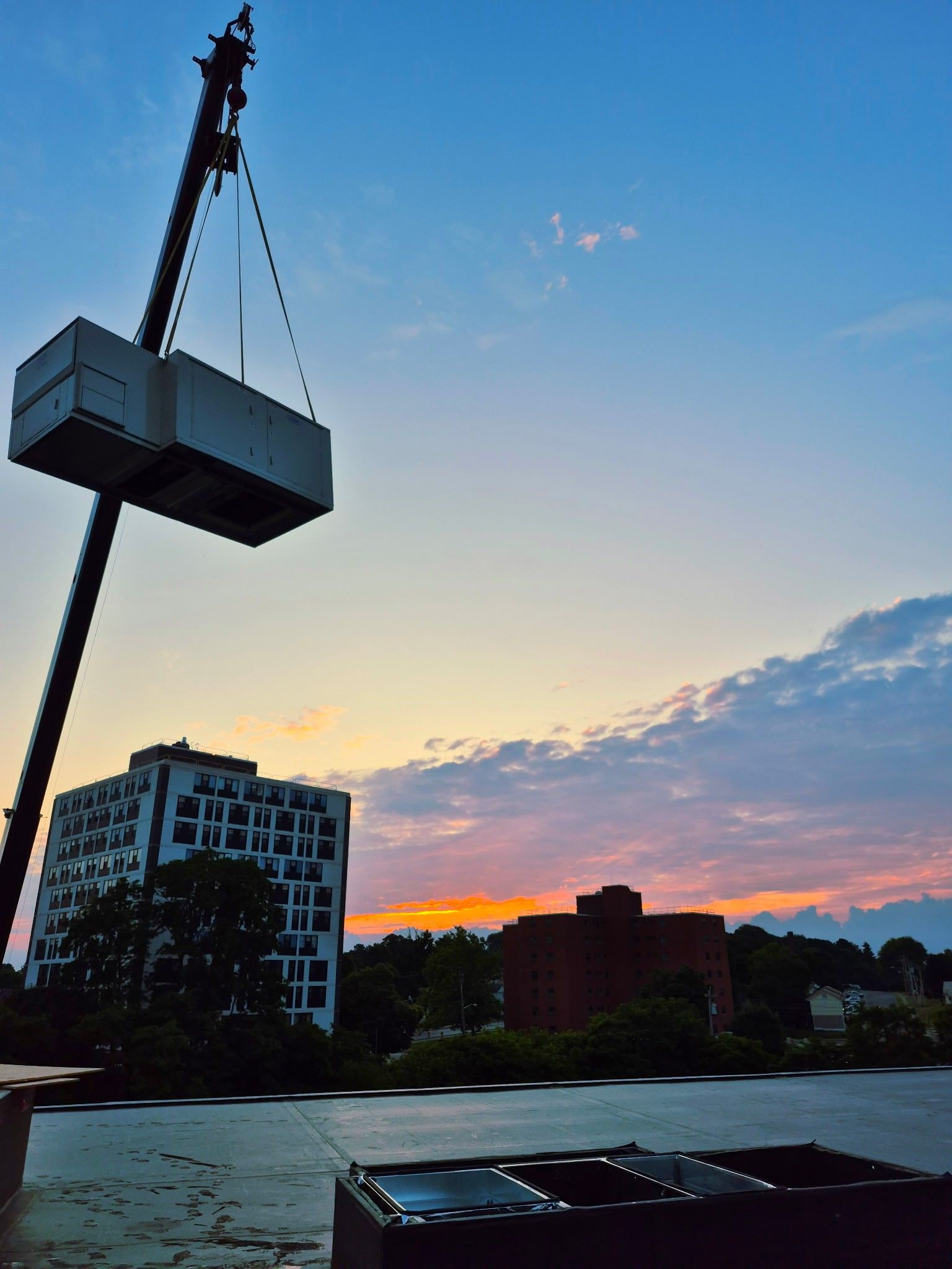 Photo of a crane lifting a box with a sunset in background