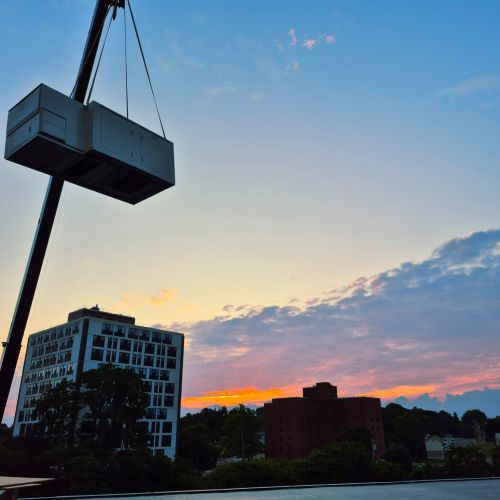Photo of a crane lifting a box with a sunset in background
